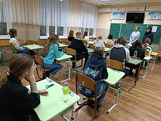 Schüler*innen in einem Klassenraum. Die Fenster sind mit Sandsäcken geschützt.