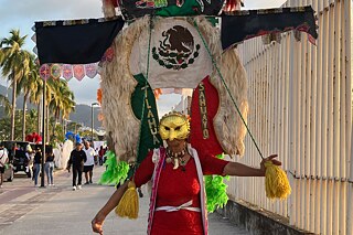 Verkleidete Person mit goldener Maske und rotem Kleid